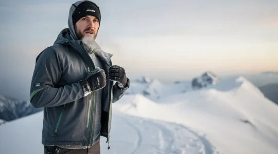 Randonneur en montagne par grand froid, ajustant ses couches de vêtements pour rester au chaud et au sec.
